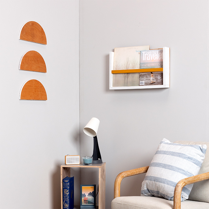 Maker-made magazine rack built from short boards mounted on wall adjacent to half circle wall decor